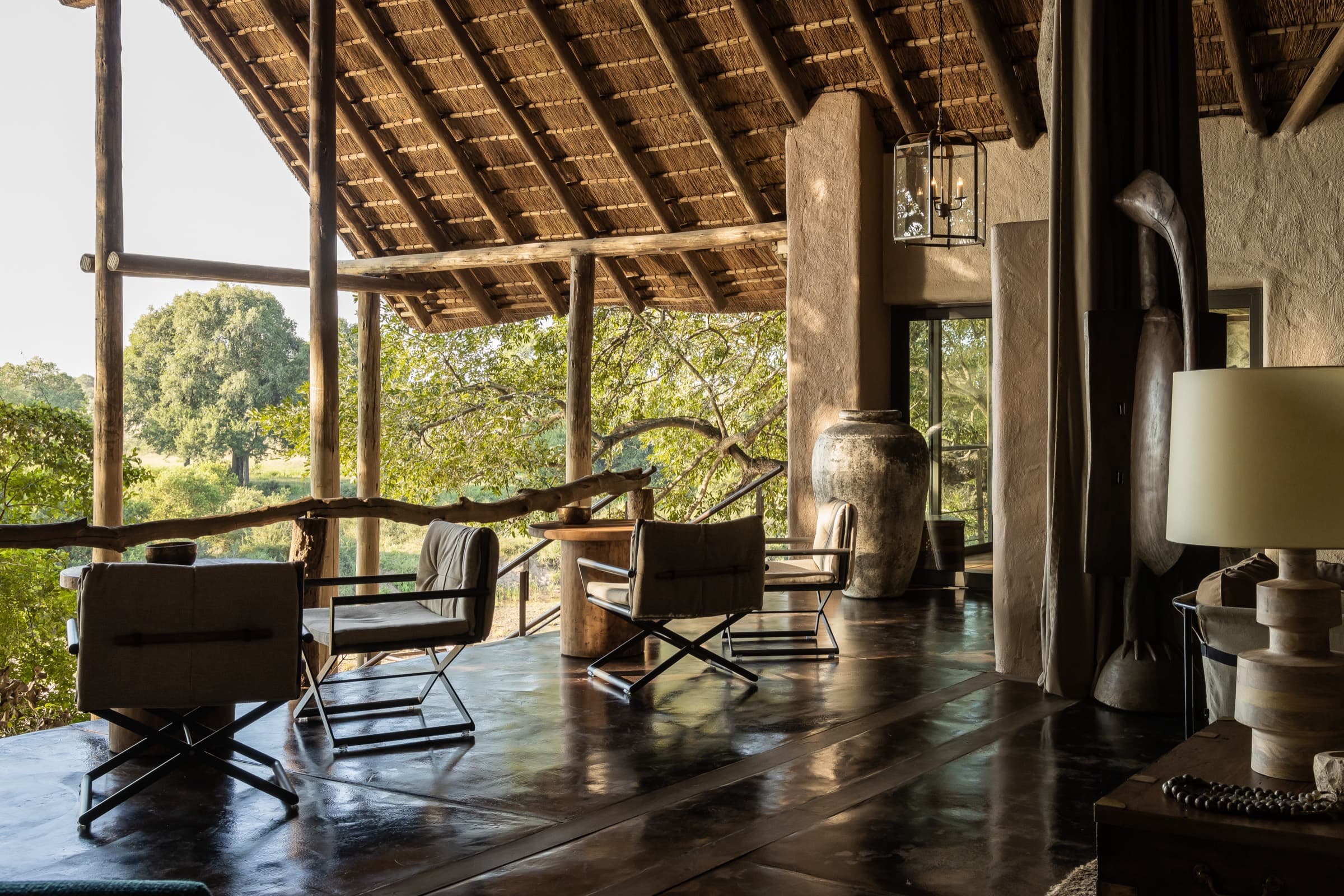 The Ebony lounge under a thatched roof, open to Sand River views